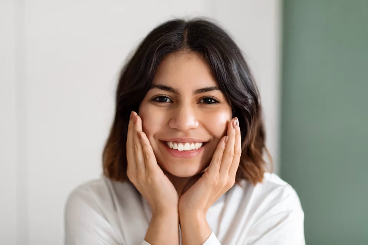 Woman smiling with her hands resting on her cheeks